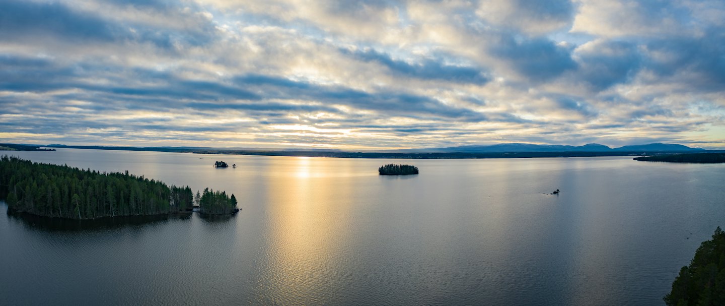 Solljus reflekteras över en sjö fylld med små skogsklädda öar.